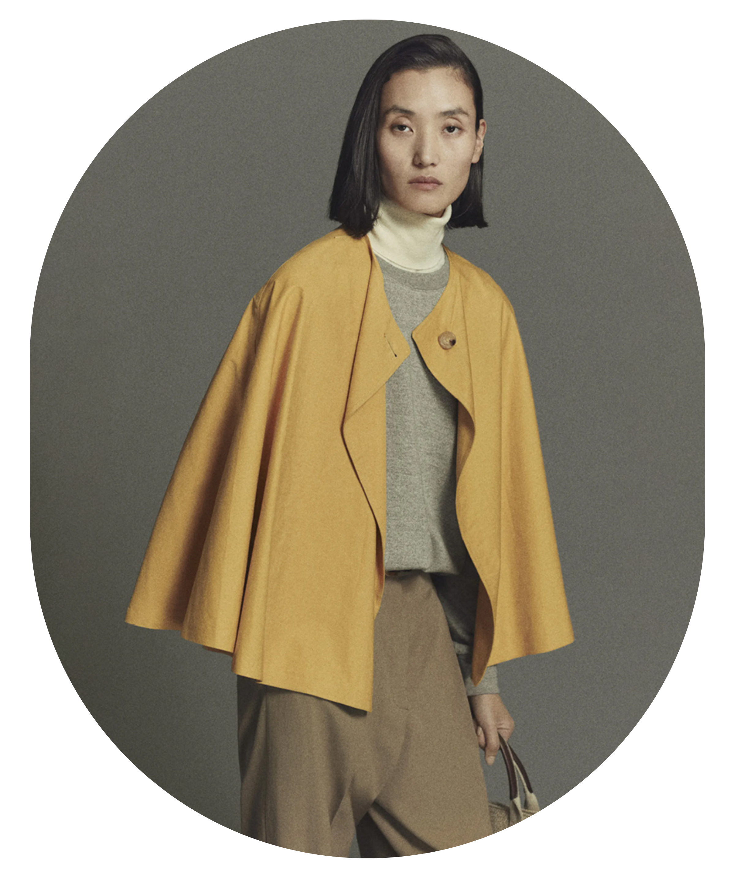 Woman wearing a mustard yellow coat against a gray background