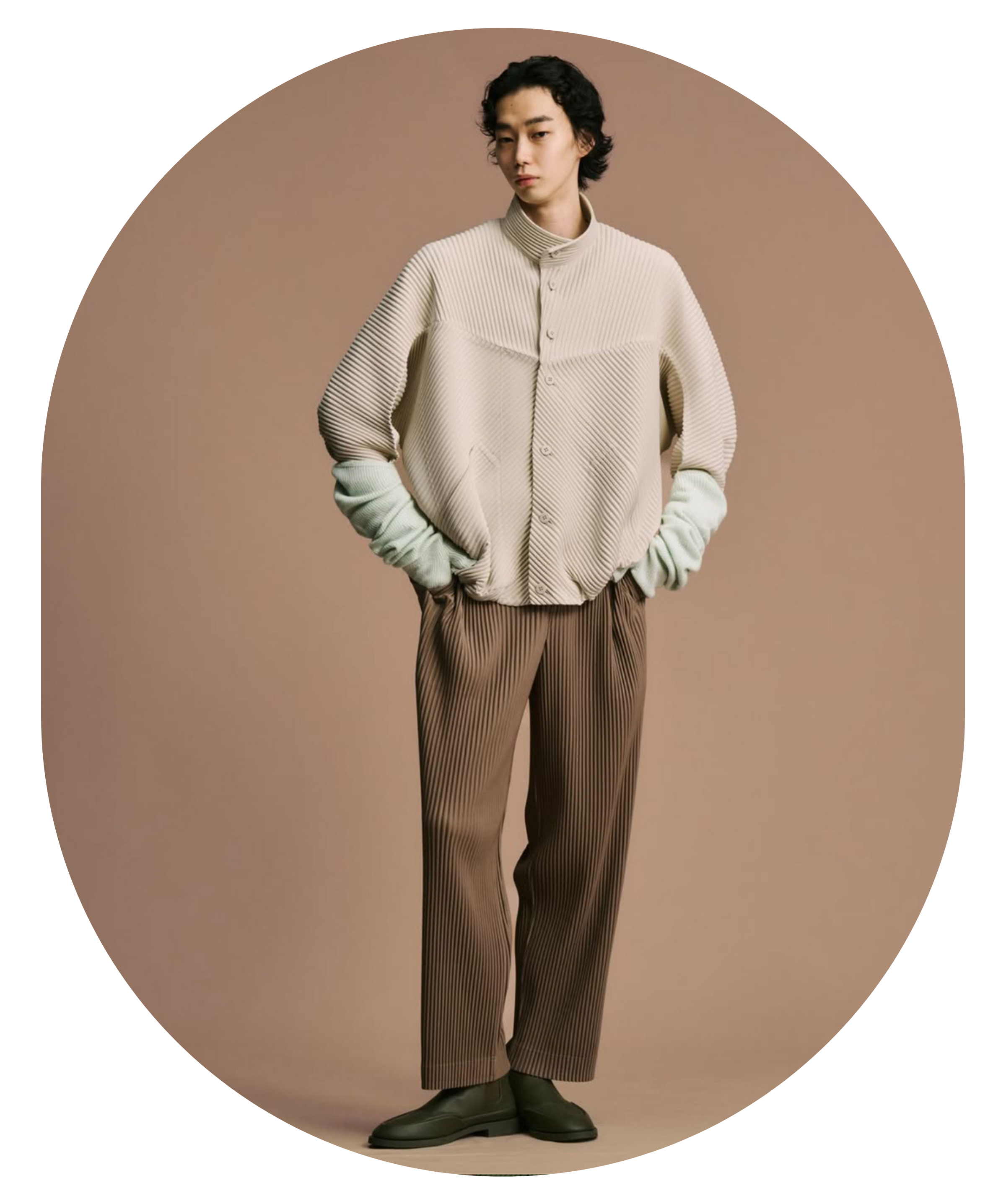 Person wearing a beige textured sweater and brown pants on a brown background