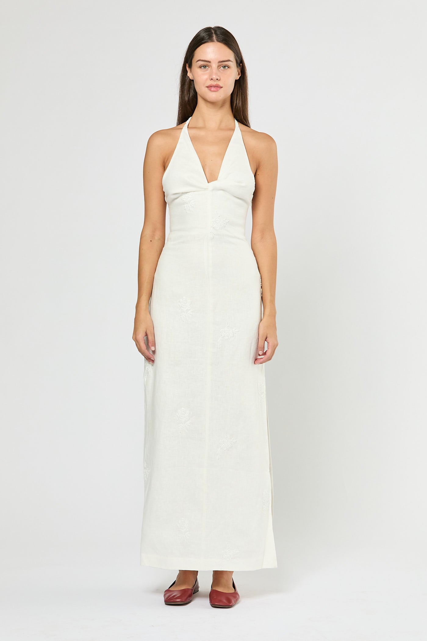 Woman wearing a white halter neck dress on a plain background