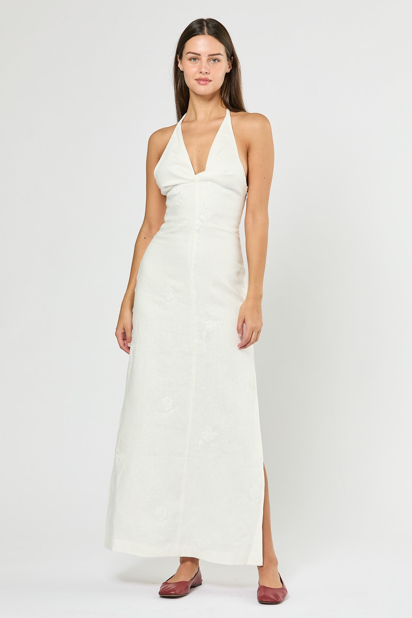 Woman wearing a white halter neck dress on a plain background