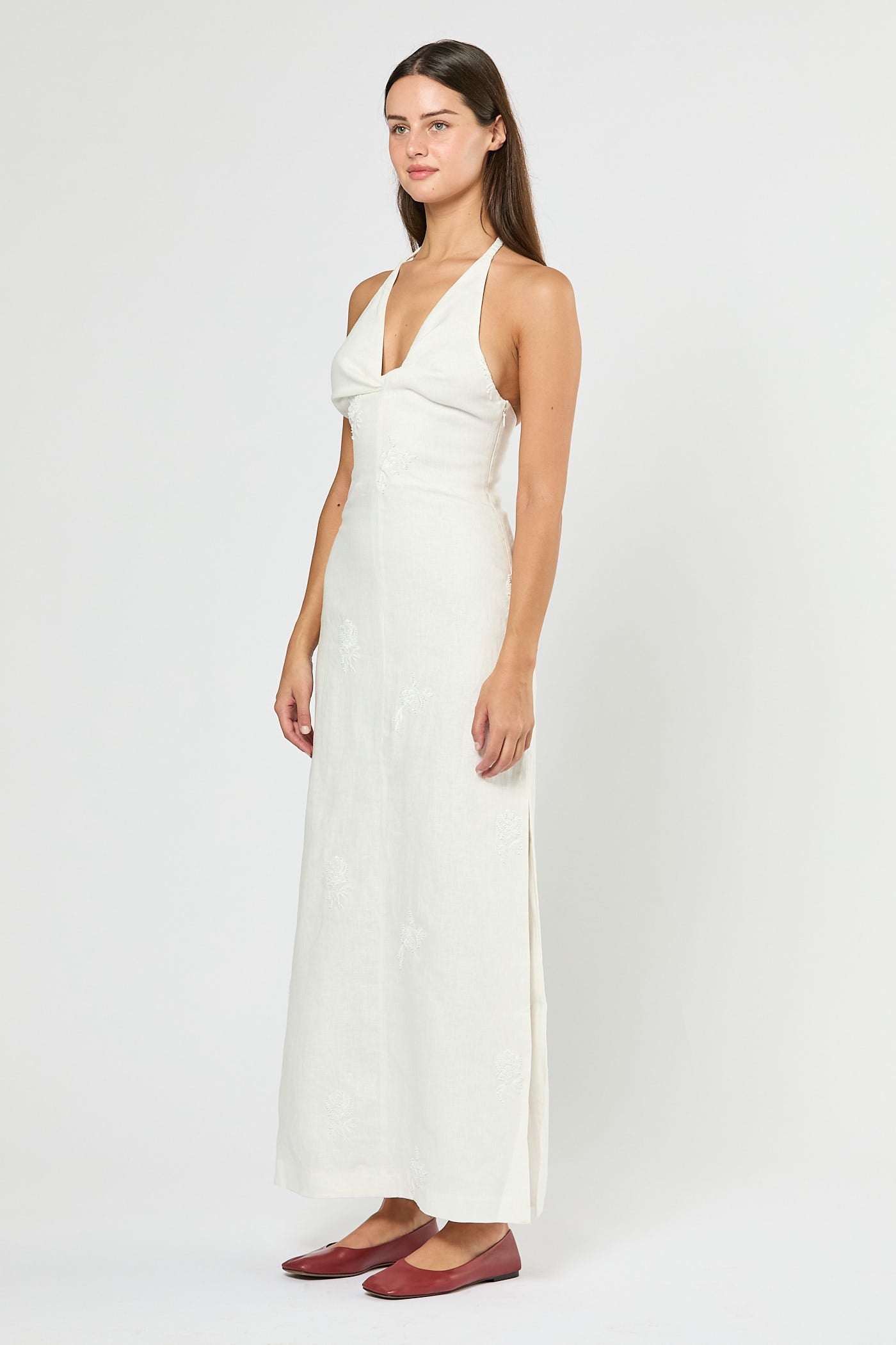 Woman wearing a white halter neck dress on a plain background