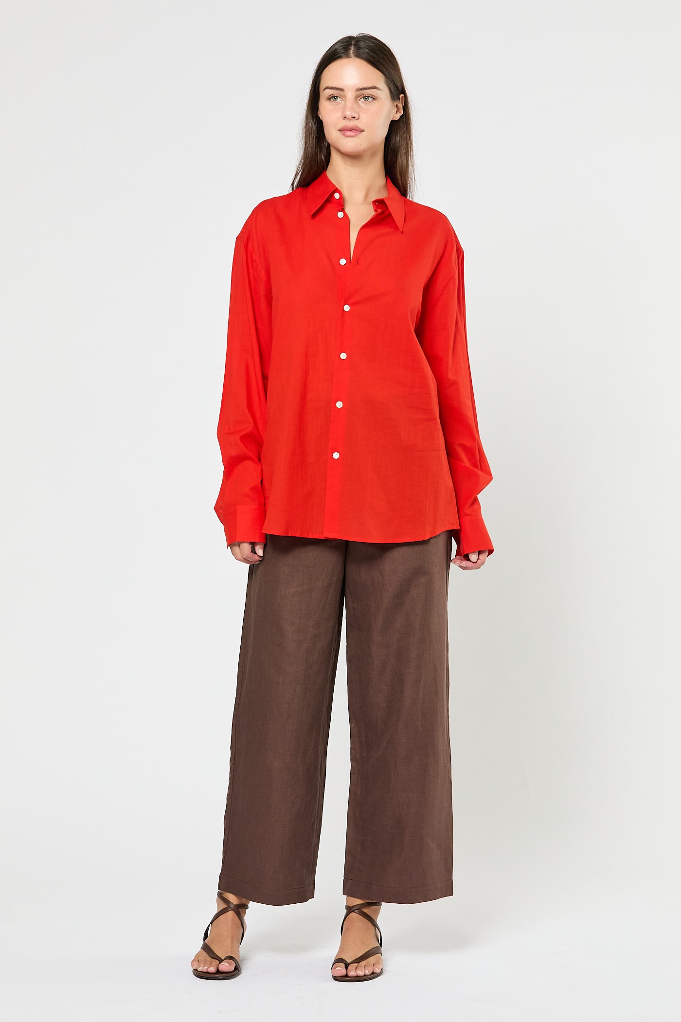 Woman wearing a red shirt and brown pants on a white background