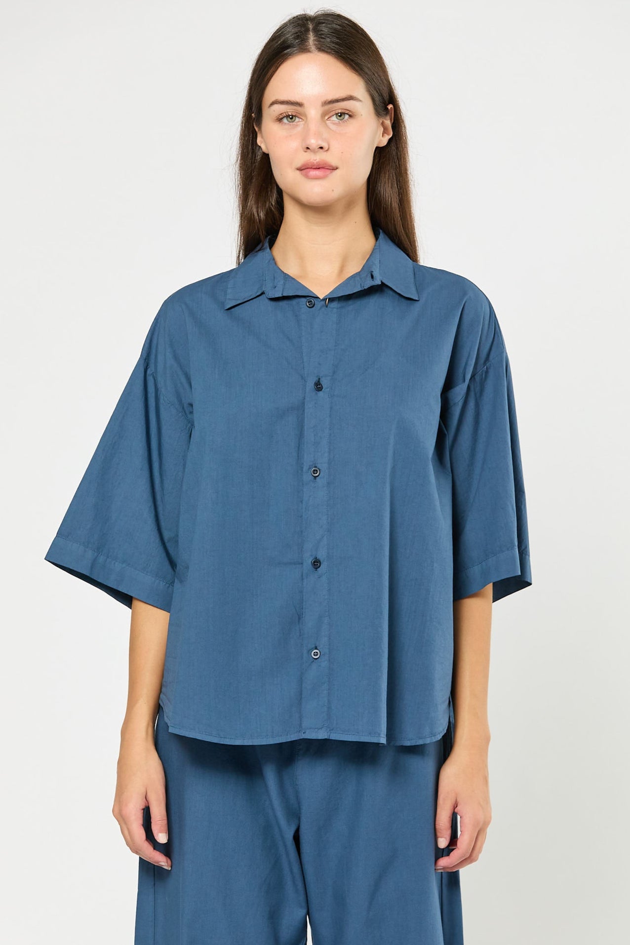 Woman wearing a blue shirt and pants on a white background