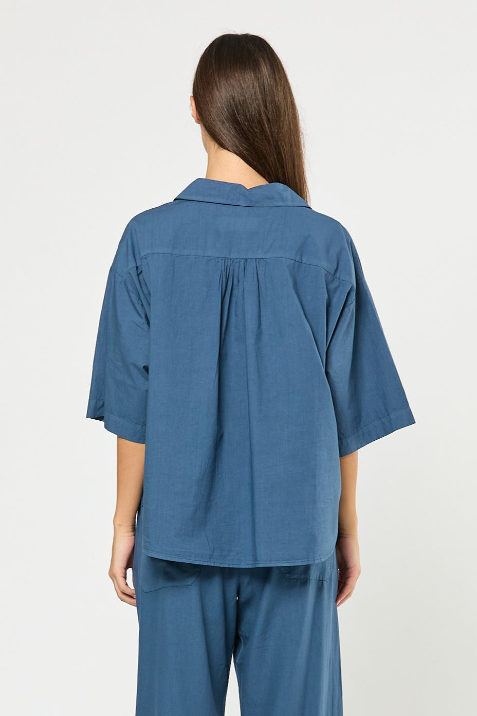 Woman wearing a blue outfit with wide-leg pants on a white background