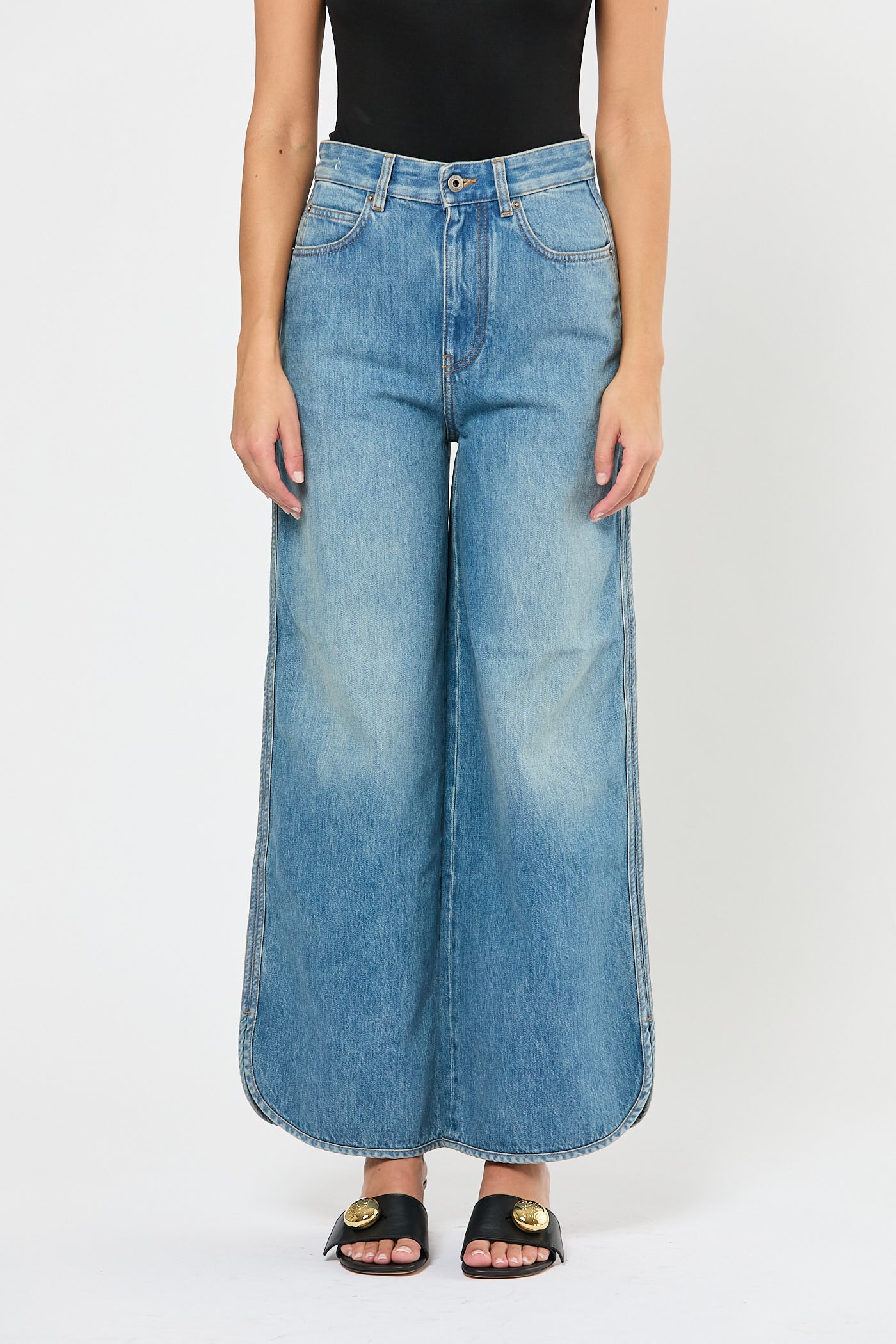 Person wearing wide-leg blue jeans on a white background