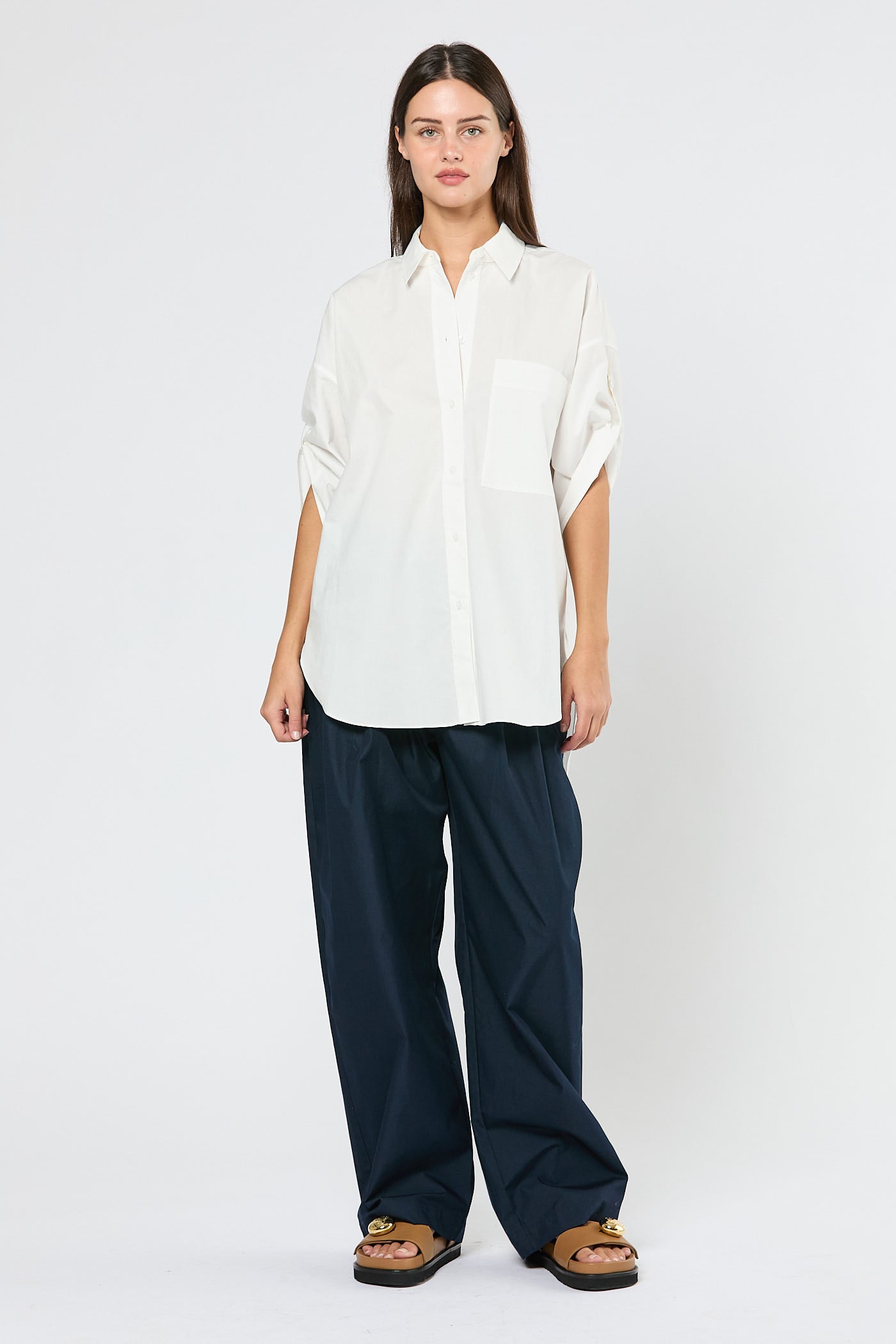 Woman wearing a white shirt and navy pants on a white background