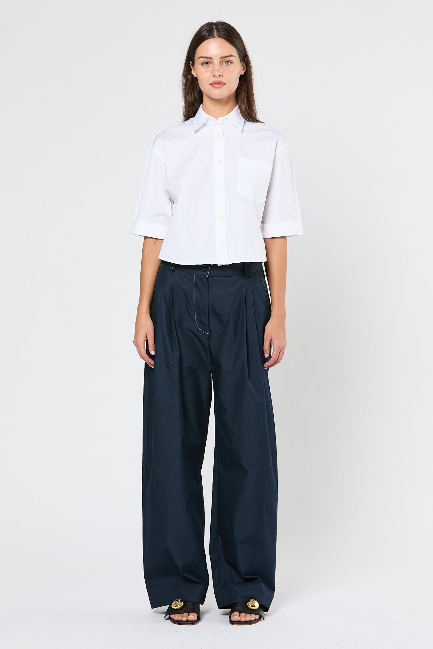 Woman wearing a white shirt and navy pants on a white background
