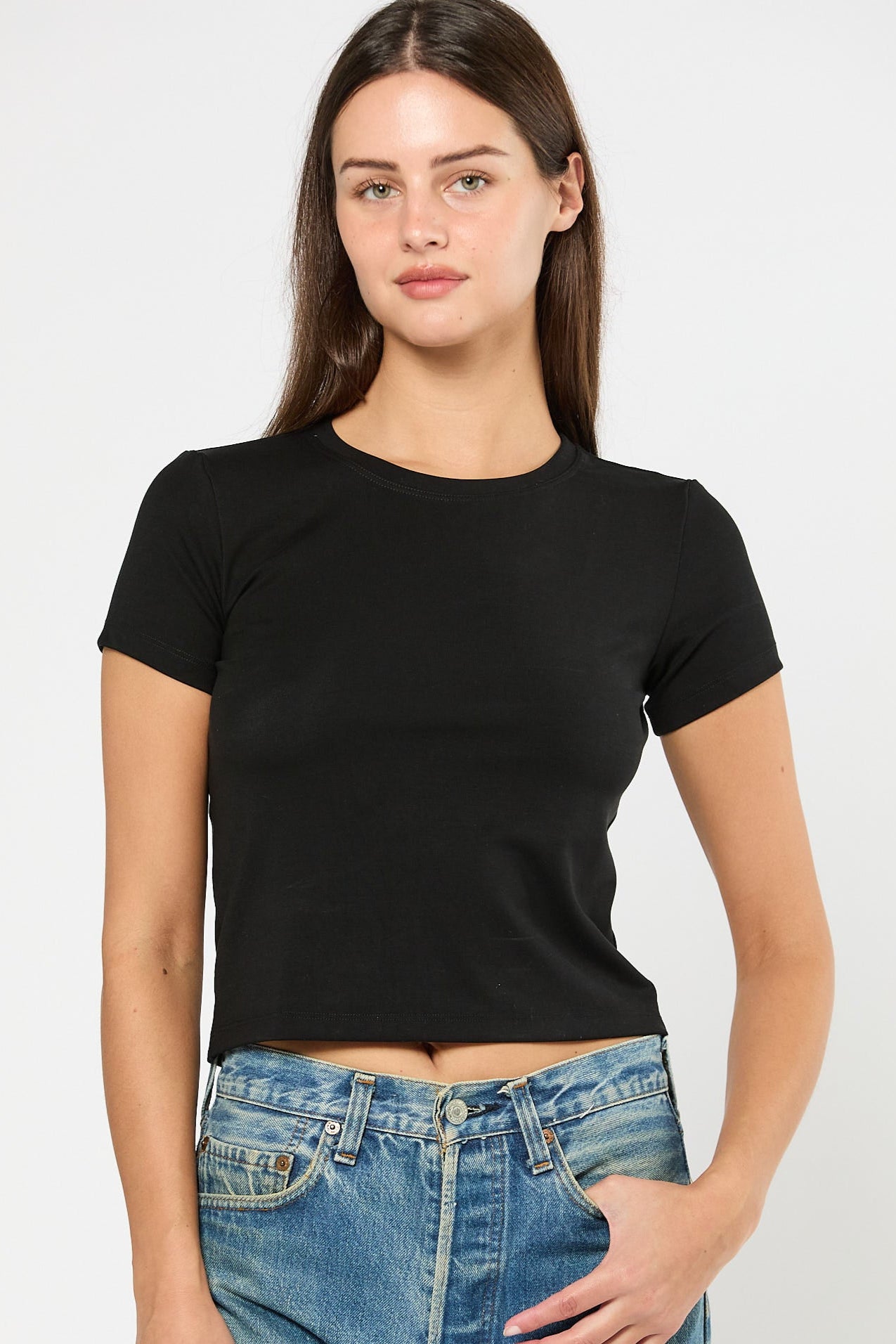 Woman wearing a black t-shirt and blue jeans on a white background