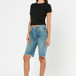 Woman wearing a black crop top and blue denim shorts on a white background