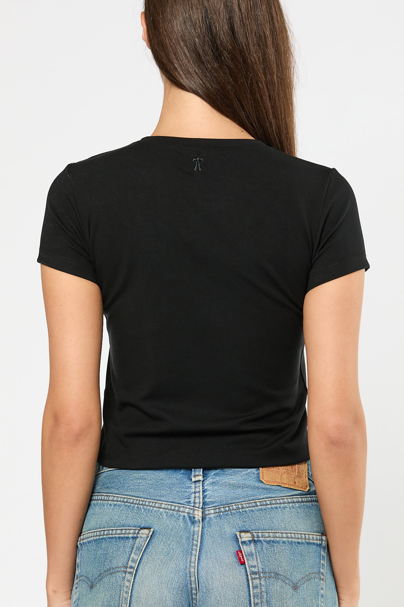 Person wearing a black t-shirt and blue jeans on a white background