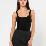 Woman wearing a black tank top and black skirt on a white background