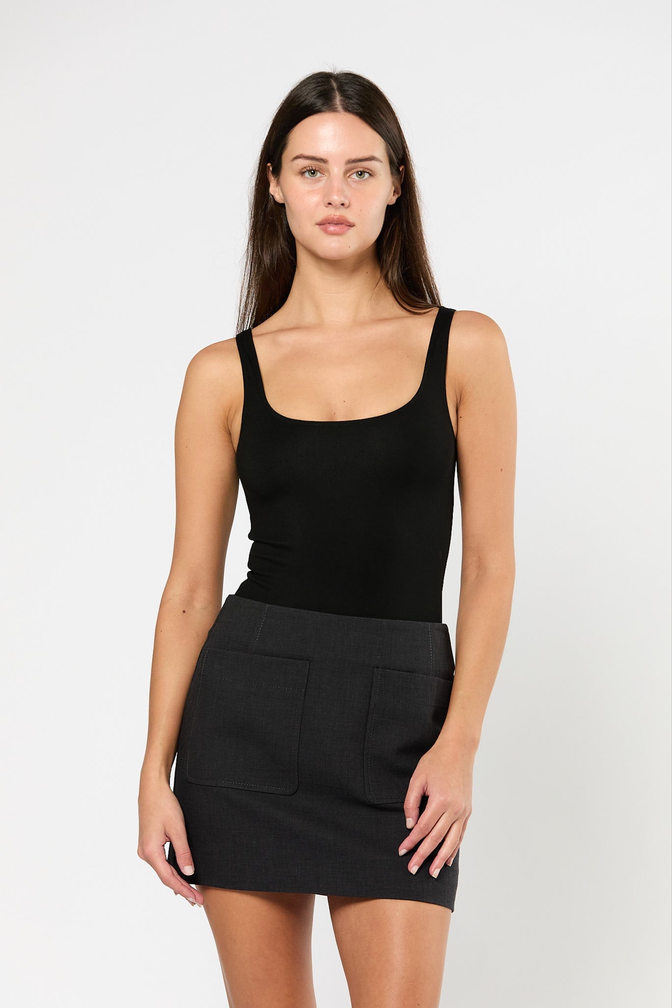 Woman wearing a black tank top and black skirt on a white background