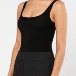 Woman wearing a black tank top and black skirt on a white background