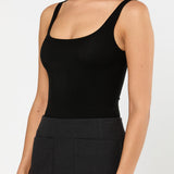 Woman wearing a black tank top and black skirt on a white background