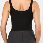 Person wearing a black tank top and gray skirt on a white background