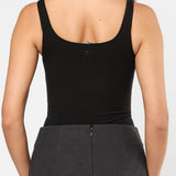 Person wearing a black tank top and gray skirt on a white background